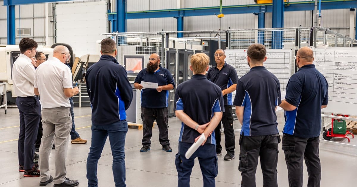 Accura Engineering team during a morning stand-up meeting on the shop floor, highlighting collaboration in advanced manufacturing.